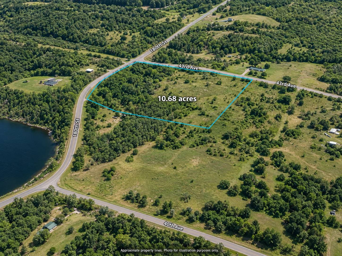 Low aerial of a 10.68-acre parcel of vacant rural land near Star Prairie in Polk County, Wisconsin, with nearby roads and a lake at the edge of the frame. Property lines are approximate.
